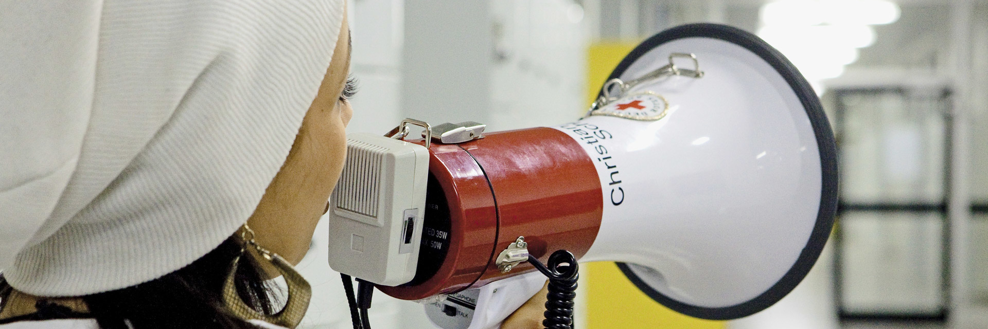 Schulsanitäterin ruft mit Megafon in Schulflur