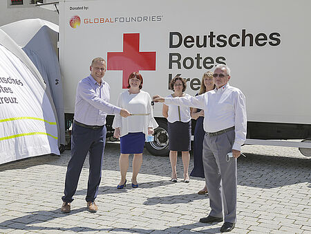 Dr. Thomas Morgenstern, Geschäftsführer von dem Chiphersteller Globalfoundries Dresden, überreicht Holger Löser, Präsident des Deutschen Roten Kreuzes in Sachsen, den Schlüssel des LKWs. Der LKW beherbergt zukünftig die Ausstattung für die mobile Corona-Teststation. Beide Herren posieren dabei für das Foto. Im Hintergrund stehen Staatsministerin für Soziales und Gesellschaftlichen Zusammenhalt, Petra Köpping und die Oberbürgermeisterin der Stadt Dippoldiswalde, Kerstin Körner.