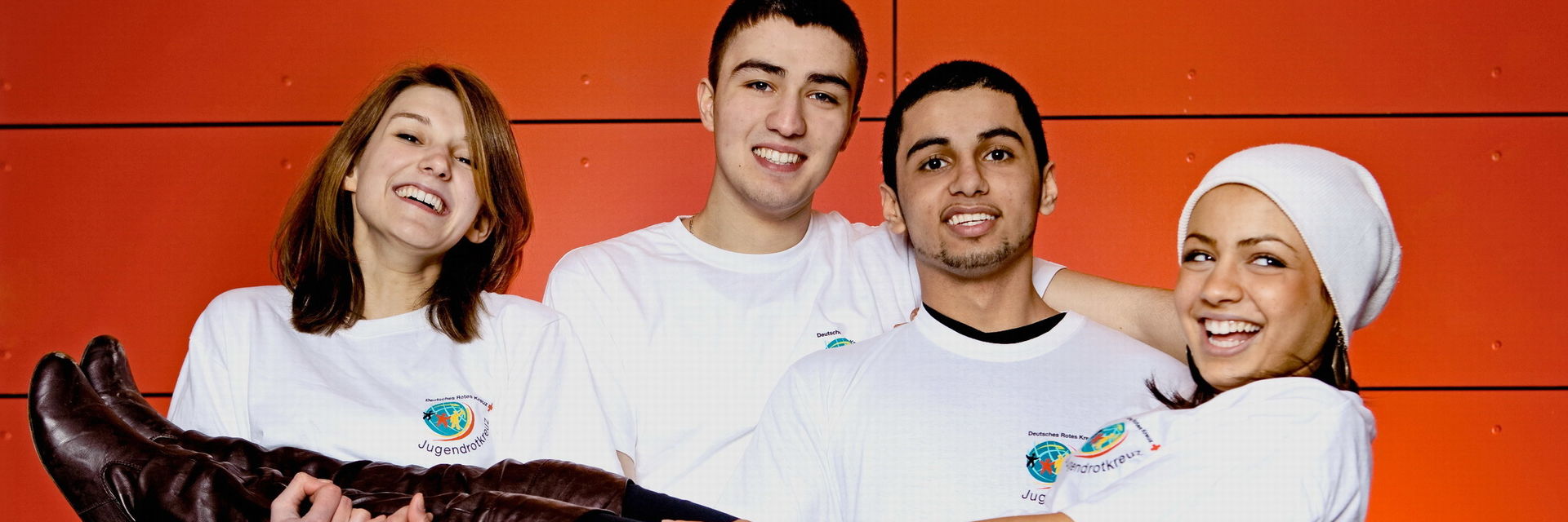 Drei Jugendliche lachen in die Kamera. Zwei halten den dritten in ihren Händen und tragen ihn.