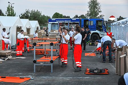 Viele Helferinnen und Helfer arbeiten in einer Zeltstadt für geflüchtete Menschen. 