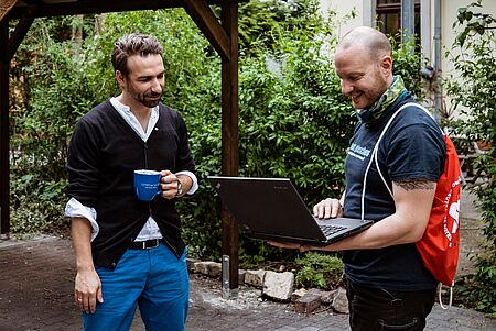 Der Geschäftsführer von Experts & Talents in Dresden übergibt einem Familienvater von 4 Kindern einen Laptop. Experts & Talents ist ein Unternehmen, welches Personal vermittelt.