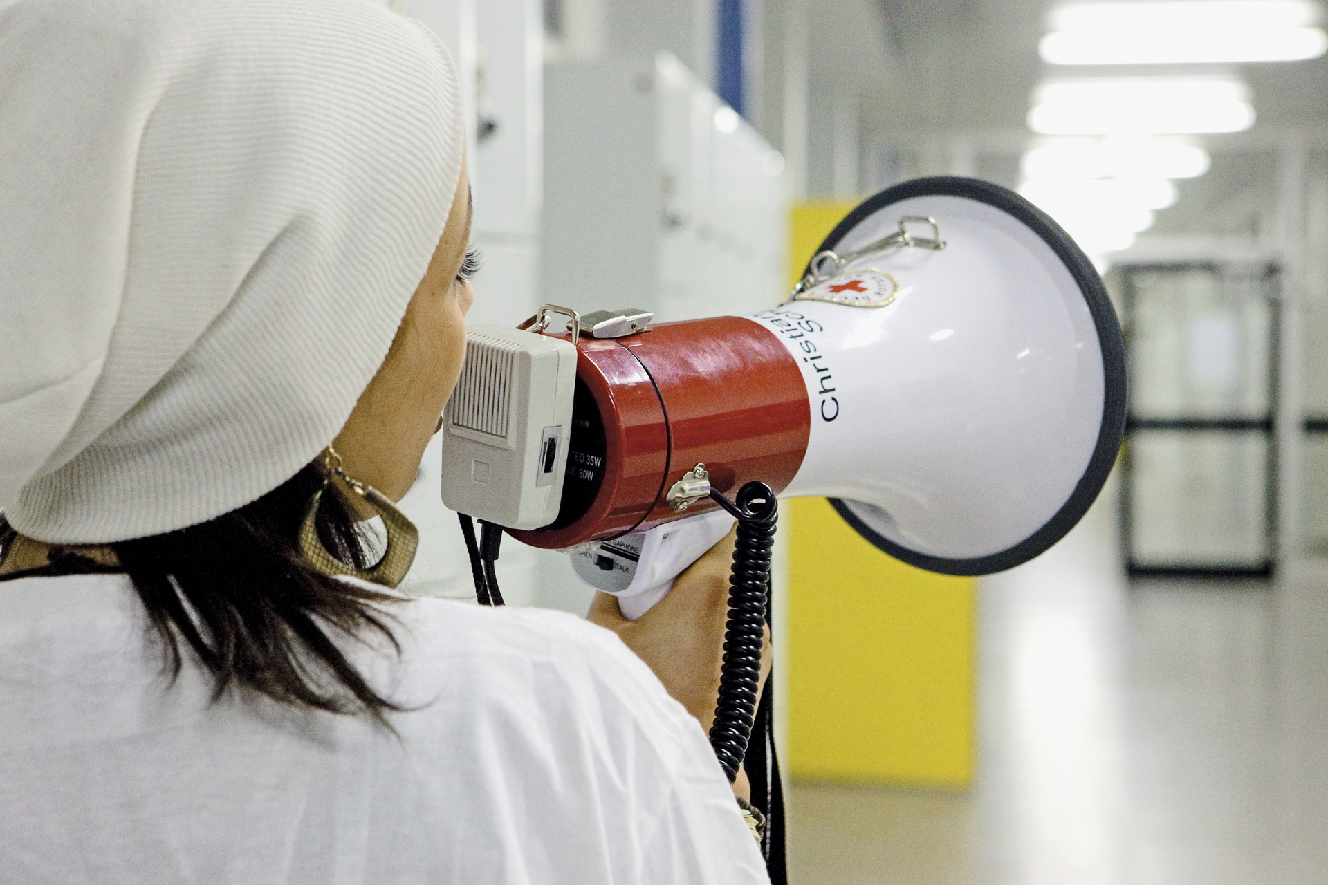 Schulsanitäterin ruft mit Megafon in Schulflur